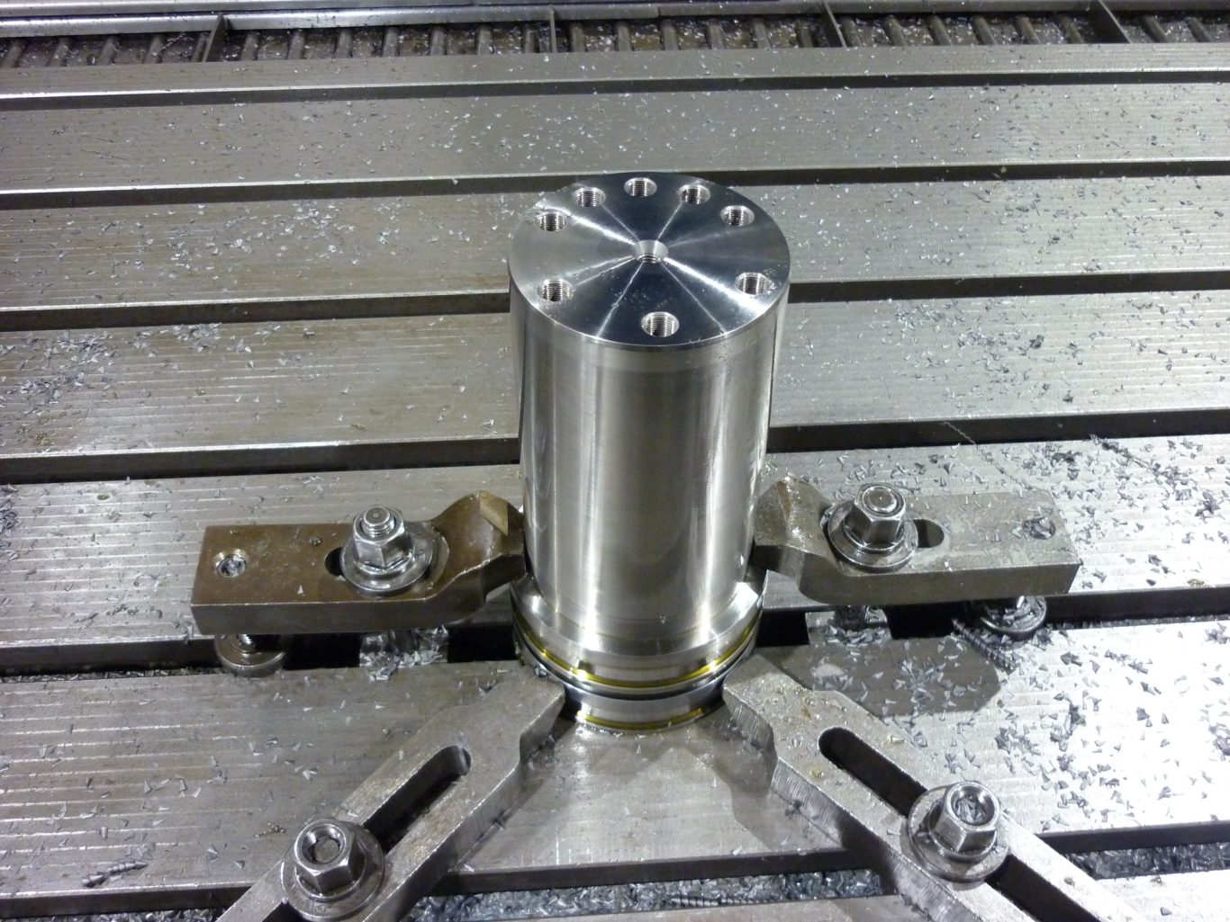 CNC-Bohren von Werkstück Metallzylinder auf einer Maschinenplatte mit Bearbeitungsspuren.