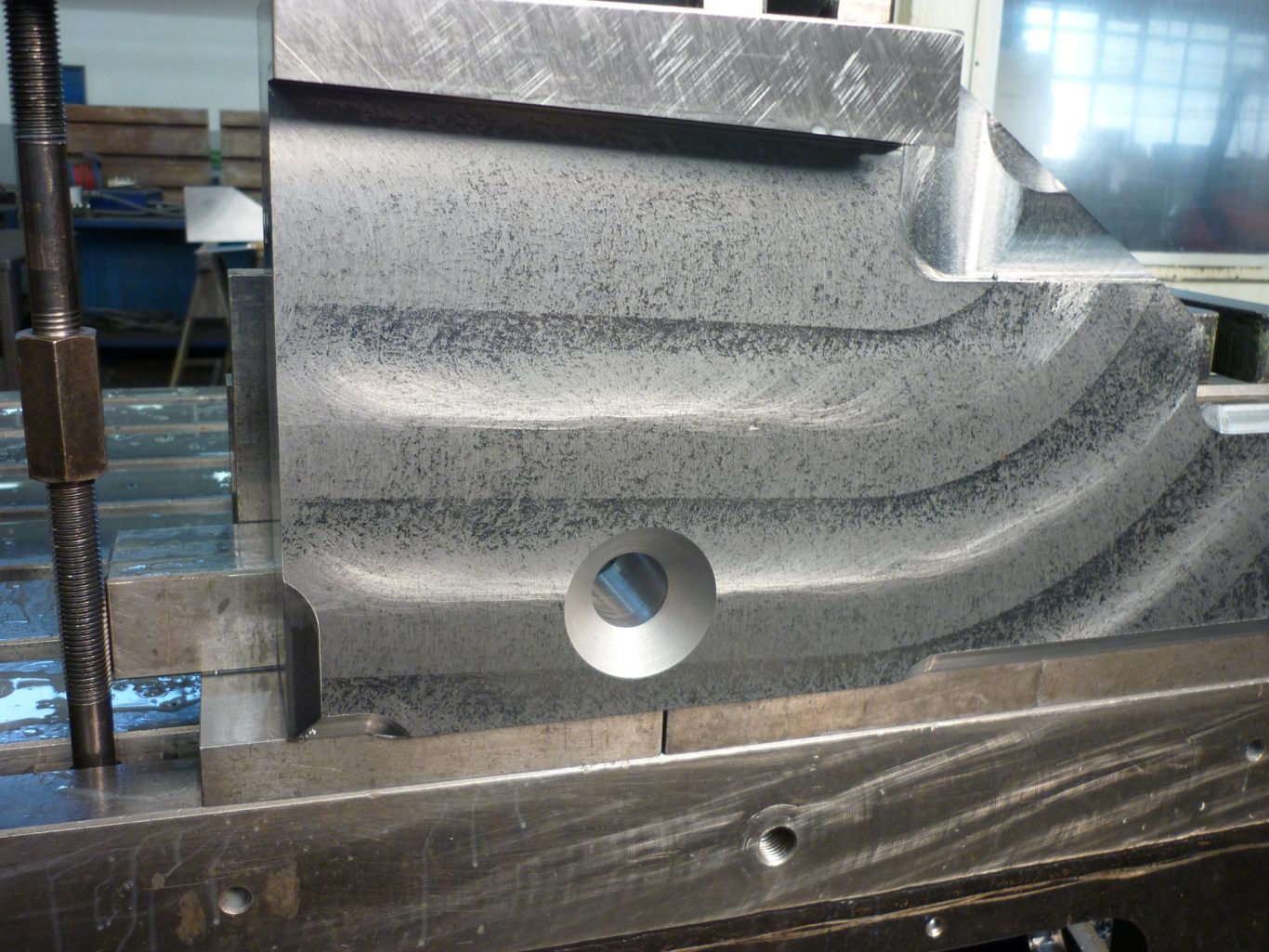 metallisches Werkstück nach CNC-Zerspanung Detaillierte Metalloberfläche mit verschiedenen geometrischen Vertiefungen und Löcher.