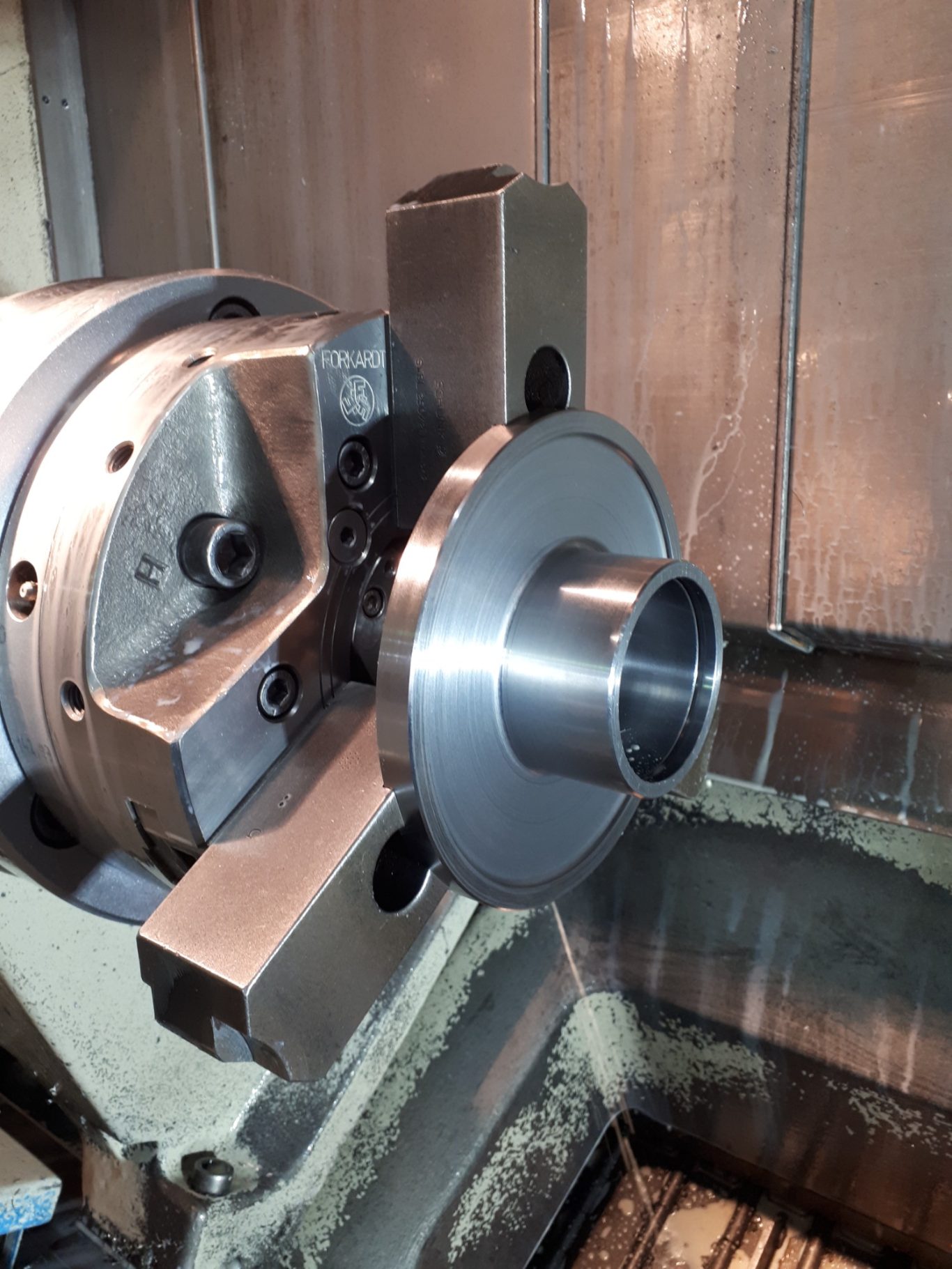 Werkstück nach der Drehbearbeitung Präzise CNC-Drehmaschine mit einem Metallwerkstück im Bearbeitungsprozess.