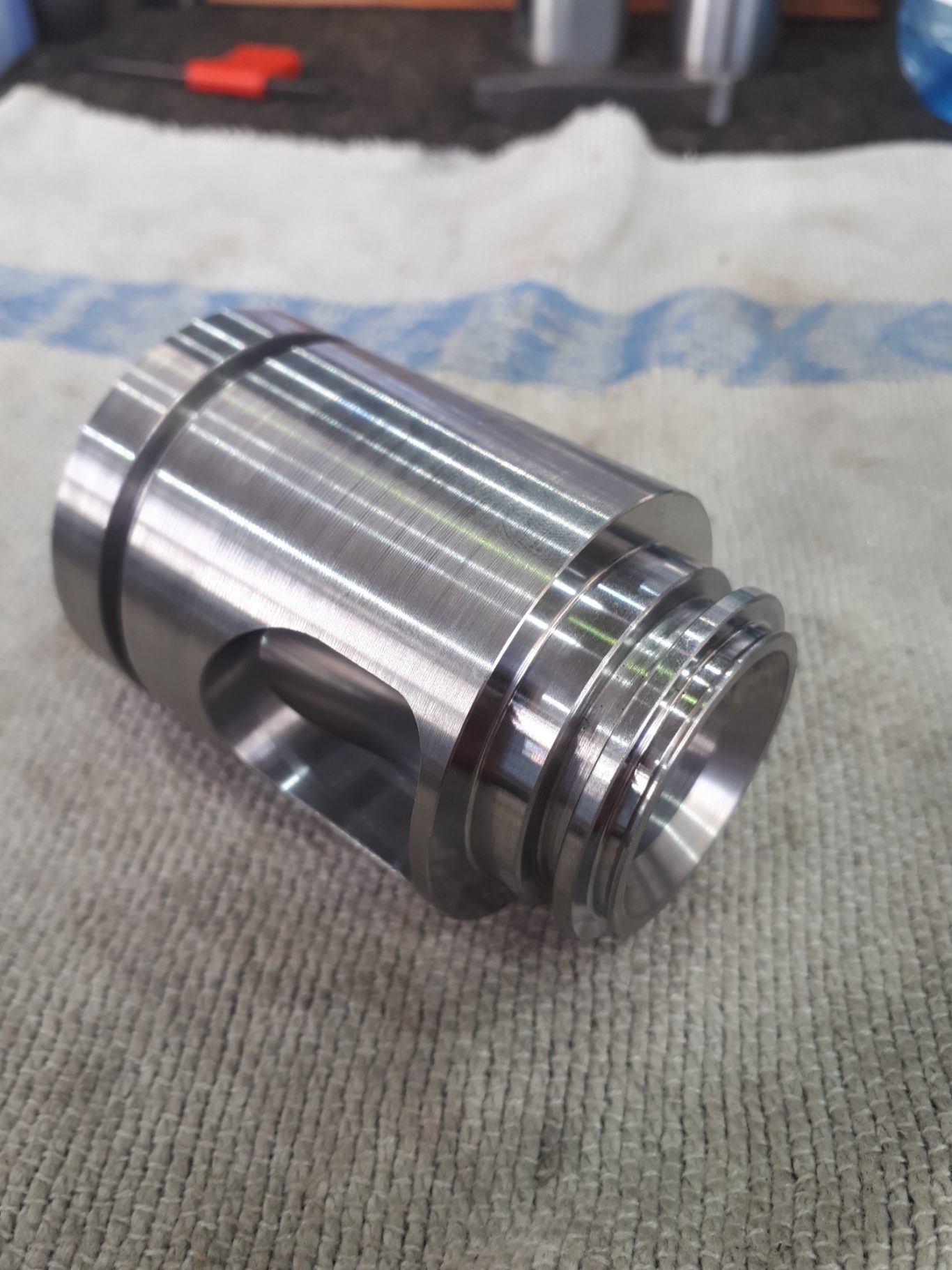 präzises Dreh-Fräs-Werkstück Ein glänzendes, zylindrisches Metallteil auf einem grauen Tuch.