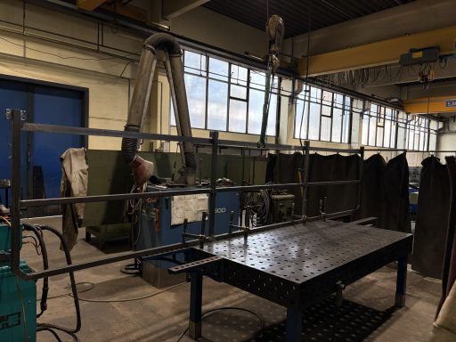 Metallgestell auf Schweißtisch in einer Fertigungshalle.