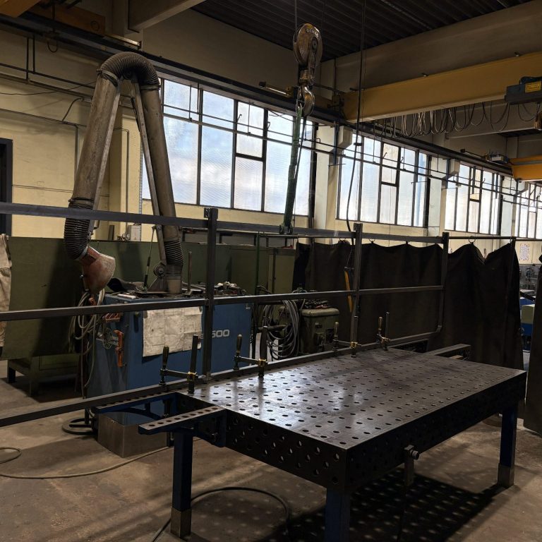 Metallgestell auf Schweißtisch in einer Fertigungshalle.