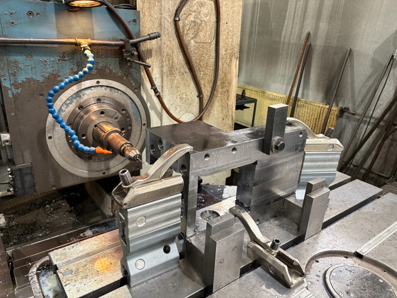 Bohrbearbeitung auf CNC-Bohrwerk CNC-Maschine mit Werkstücken und Kühlmittelzufuhr in einer Werkstatt.