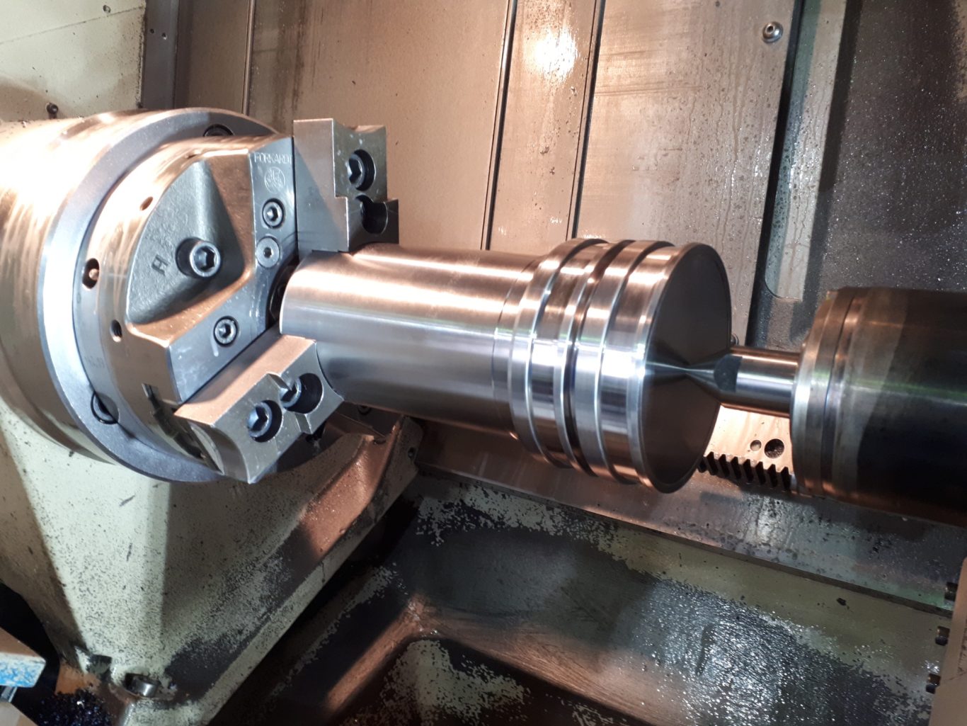 CNC-Drehteil mit Reitstockzentrierung Eine Präzisionsdrehmaschine mit einem bearbeiteten Metallwerkstück.